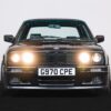 BMW E30 325i Sport front angle with headlights illuminated