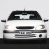 Front angle of white Citroen Saxo VTS Phase 2 with headlights on, available to win at Redline Competitions.