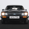 Front view of a 1984 Ford Capri 2.8i with headlights turned on, black with red coachline.
