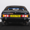 Rear view of a black 1984 Ford Capri 2.8i with red coachline in a UK competition.