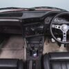 BMW E30 M-tech II red interior showing dashboard, steering wheel, 5-speed gearstick, and pedals – Redline Competitions