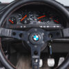 BMW E30 M-tech II red close-up of BMW Prototipo steering wheel – Redline Competitions