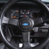Steering wheel and dashboard close-up of Radiant Red Ford Sierra Sapphire UK competition car.